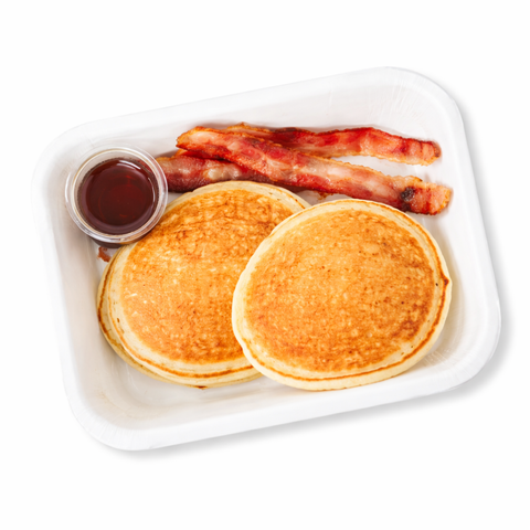 Two pancakes with bacon and syrup on a white plate