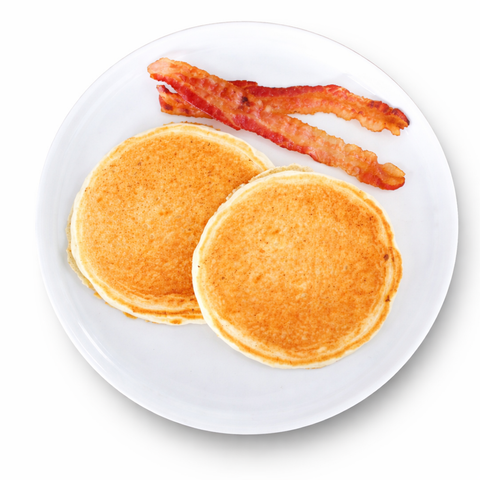 Two pancakes with two strips of bacon on a white plate