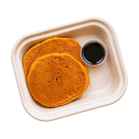 Pumpkin pancakes packaged in a meal-prep tray with maple syrup on the side, a gluten-free dairy-free breakfast from luxe + lemons.
