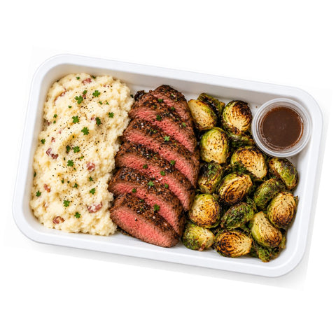 Seared steak meal prep container with dairy-free mashed potatoes and roasted brussels sprouts, a gluten-free high-protein entree by luxe + lemons